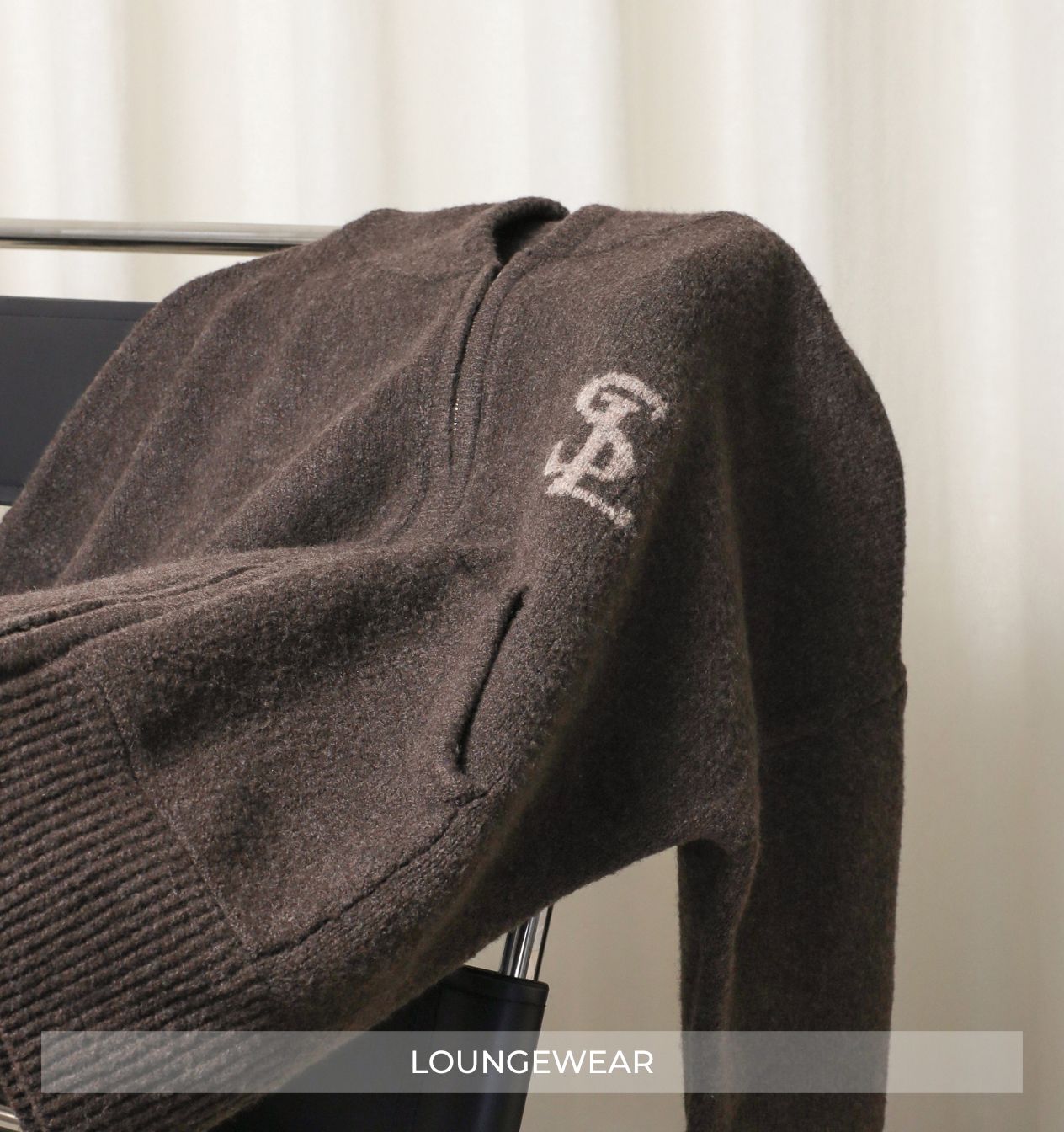 Brown loungeewear jacket with a logo on a hanger against a neutral background