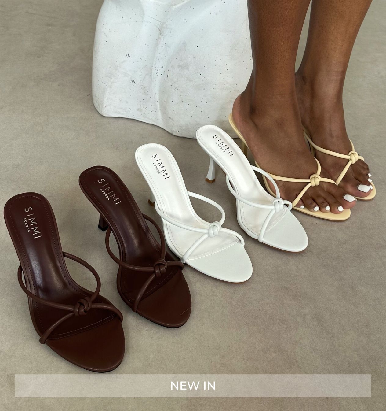 Three pairs of women's sandals in brown, white, and beige on a neutral background.