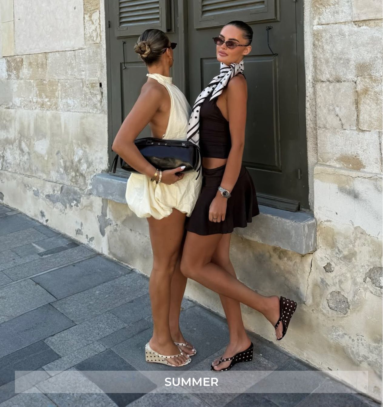 Two women standing on a stone step with a stone building in the background, labeled 'Summer'.