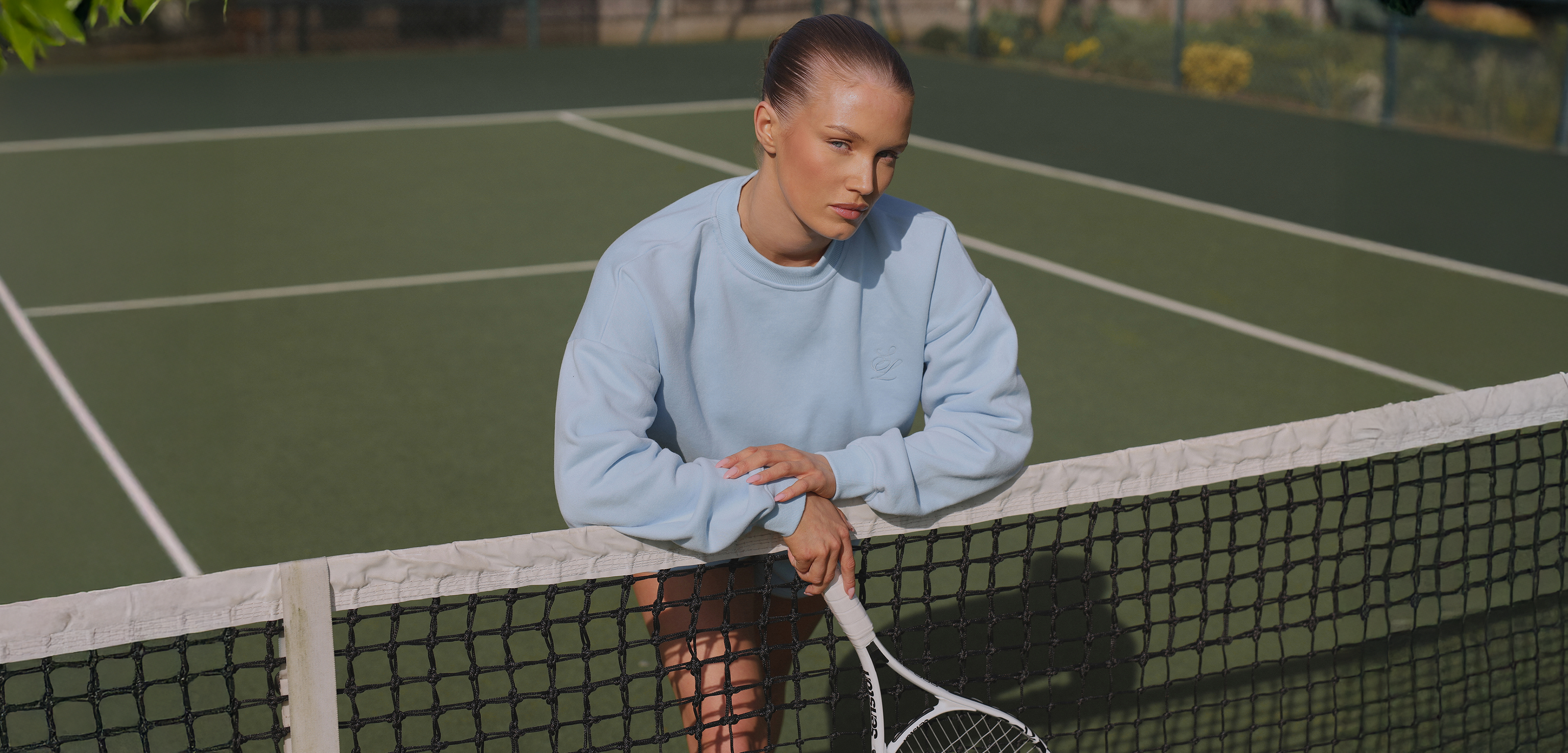 Woman sitting on a tennis court holding a racket