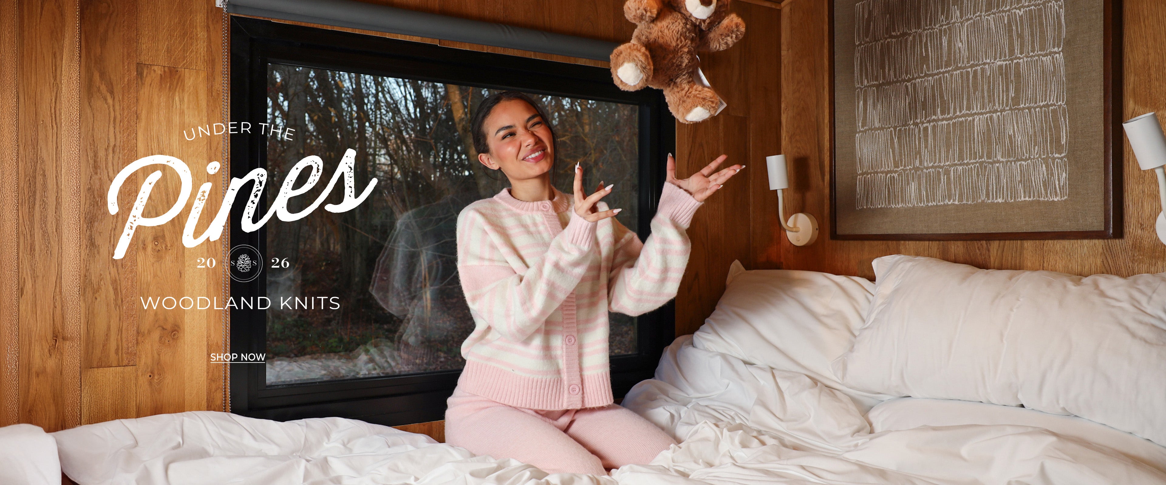 Person in pajamas sitting on a bed with a TV displaying 'Under the Pines' in the background