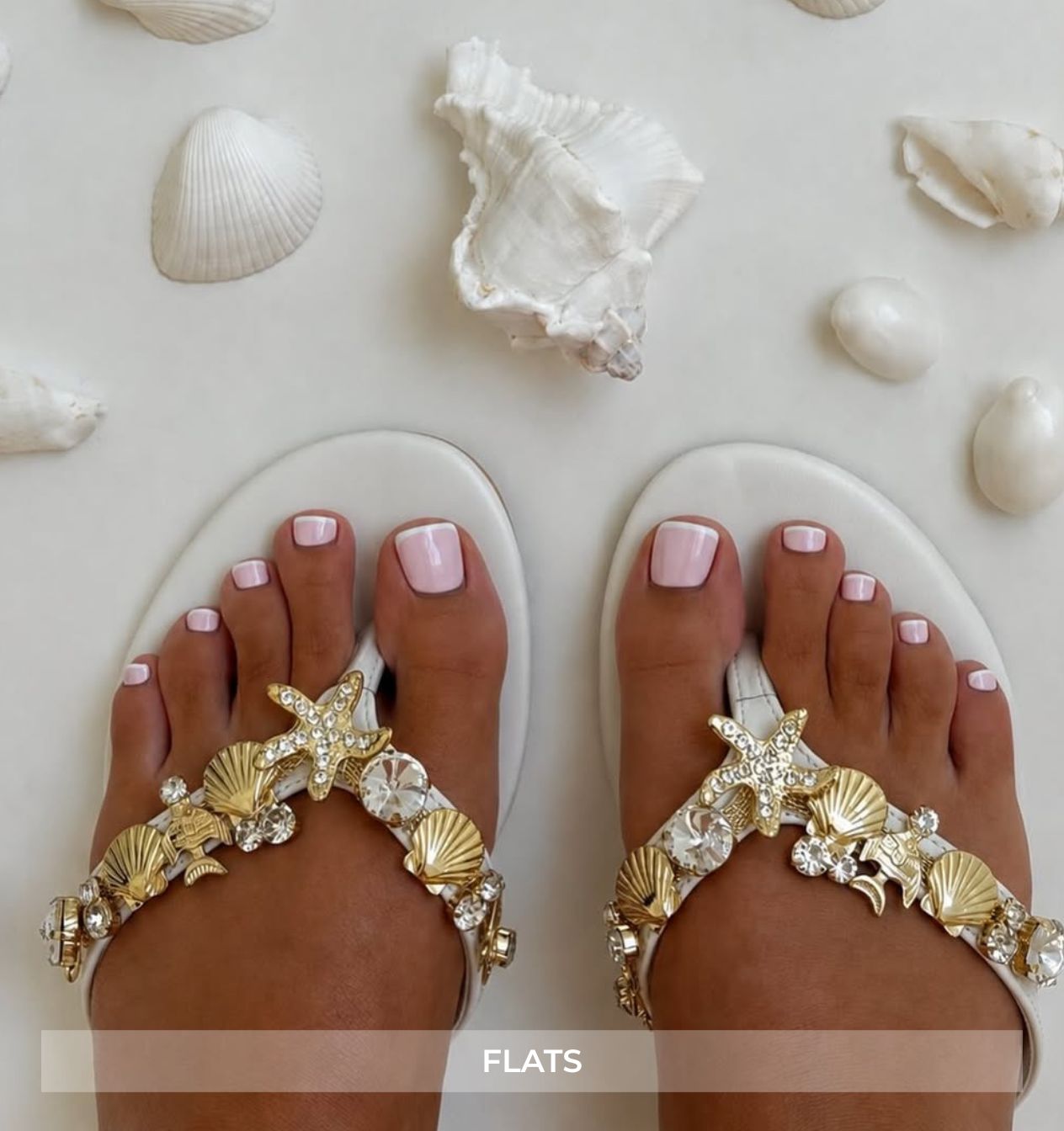 Decorative sandals with shell and starfish designs on toes, surrounded by seashells.