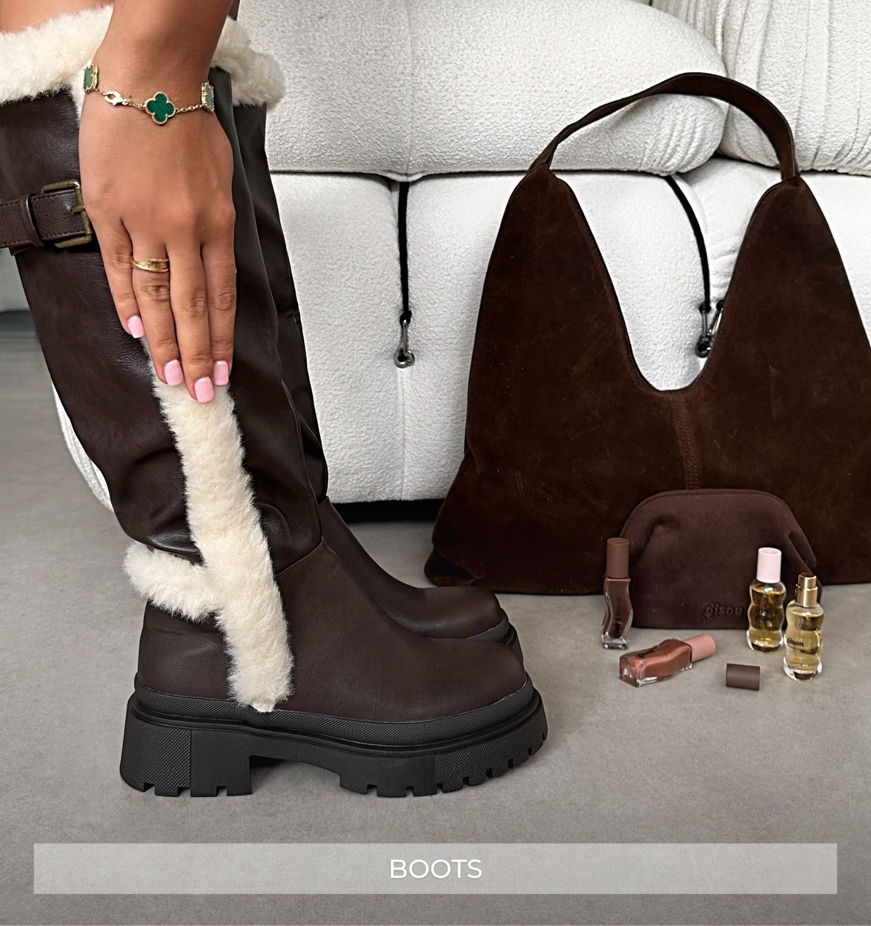 Brown knee-high boots with white fur lining, brown handbag, and small pouch on a gray surface.