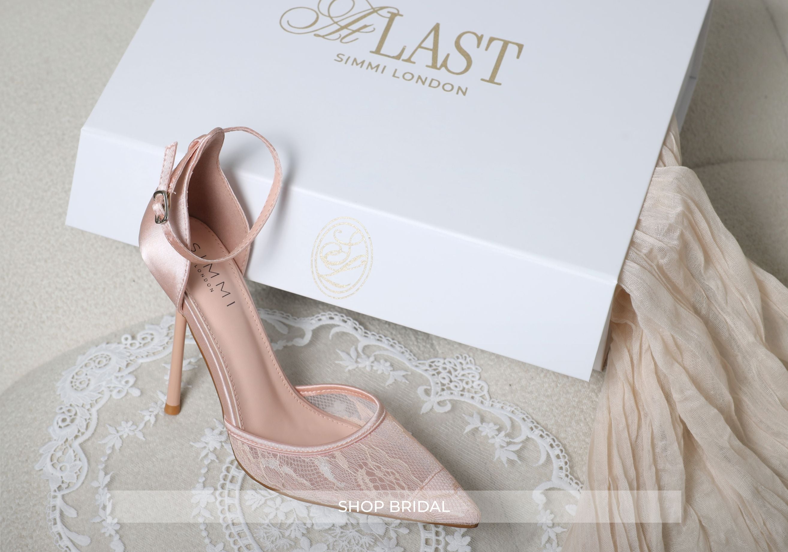 Pink high-heeled shoes with lace detail on a white box with 'Last Simmi London' branding.