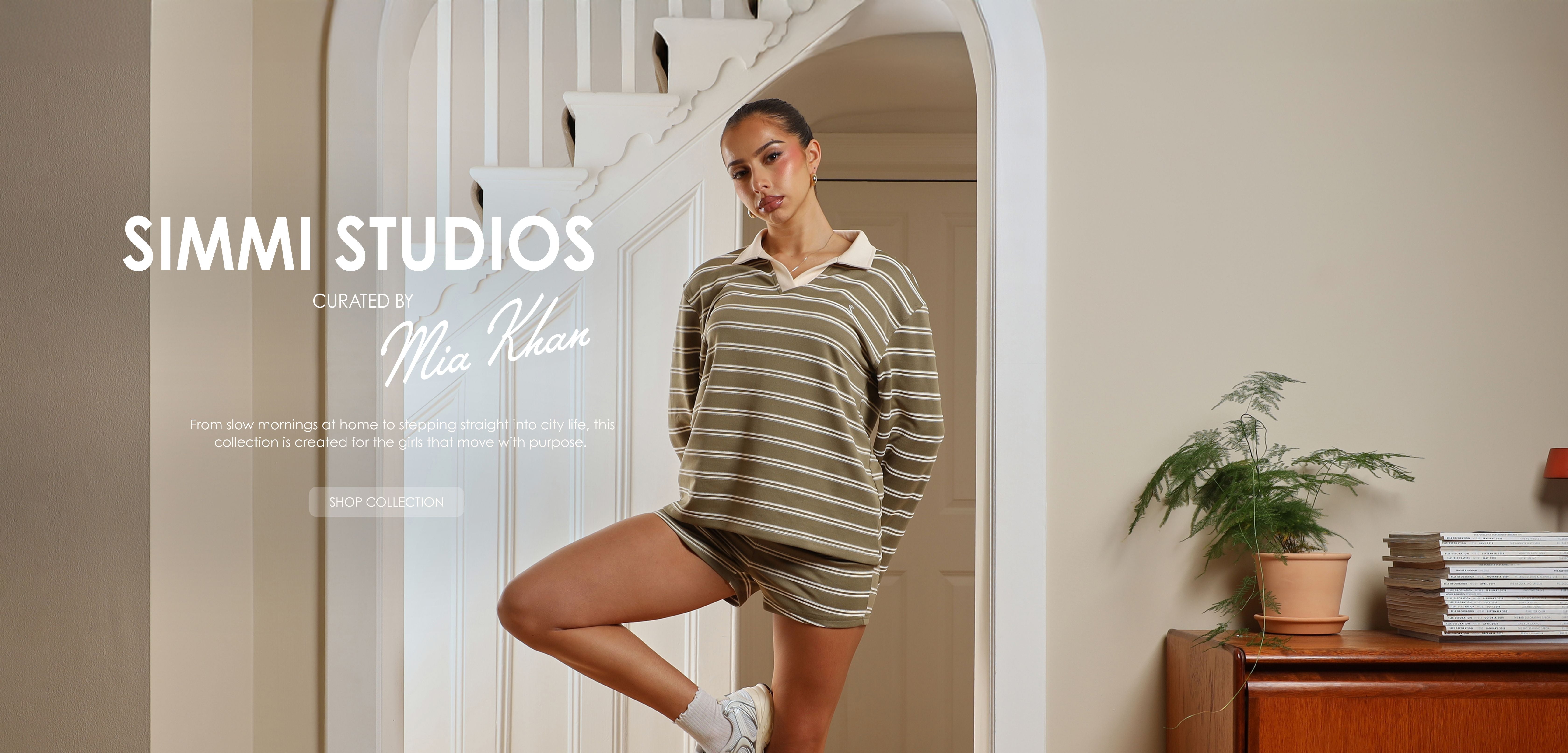 Woman posing in a room with a mirror and books on a shelf.
